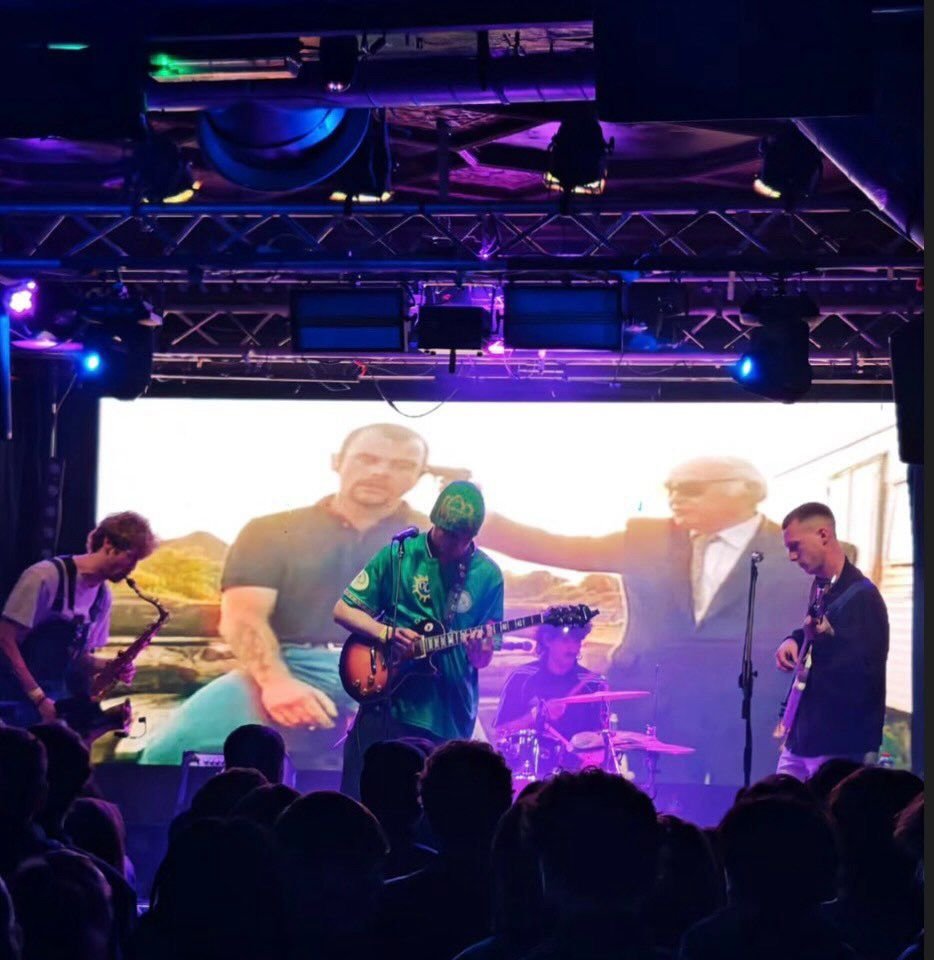 Full band on stage with LED backdrop and crowd